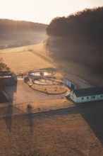 Wastewater treatment plant in a rural area in morning light with long shadows and light fog,