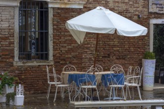 Empty seats with parasols in front of the Ghimel Garden kosher restaurant in Gheto Novo, Venice,