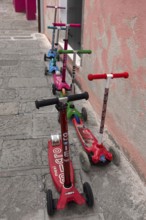 Colourful children's scooters in front of a kindergarten wall, Venice, Veneto, Italy