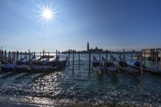 Gondolas at anchor, beginning floods, San Giorgio Maggiore church in the back, sun star, Venice,