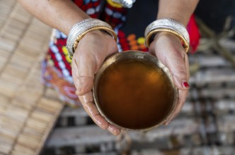 A Mising tribal woman shows their traditional rice beer 'Aapong' during Ali-Aye-Ligang festival in