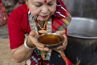 A Mising tribal woman having traditional rice beer 'Aapong' during Ali-Aye-Ligang festival in