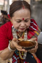 A Mising tribal woman having traditional rice beer 'Aapong' during Ali-Aye-Ligang festival in
