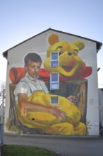 Mural Waldsterben by CASE MaClaim 2024, man with yellow plush toy, bear figure, street art,