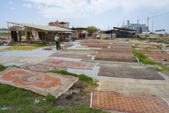Open-air market with a variety of carpets spread across grasses and pebbles, Aksaray province,