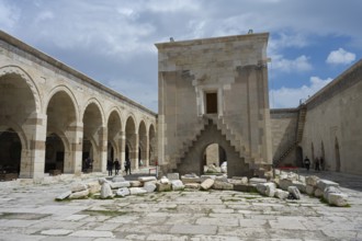 Open courtyard with arched architecture and scattered ancient stones, Sultanhani caravanserai, on