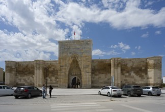 Historic fortress with an open gate, cars and passers-by in the foreground, Sultanhani