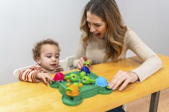 Happy mother and toddler play a colorful tabletop turtle game, smiling and learning together while