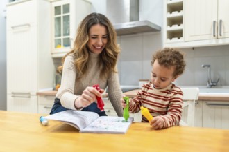 Happy mother and young son bond at the kitchen table, coloring with markers and crayons, sharing
