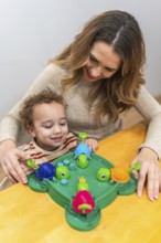 Happy mother and young son share joyful indoor play, laughing while learning with a colorful turtle