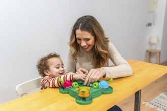 Mother and young son enjoying a playful moment, laughing and interacting while sitting at a wooden