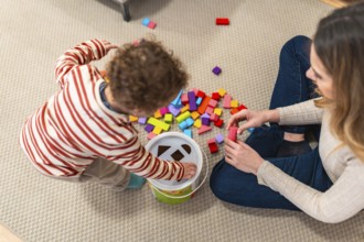 Parent and toddler bonding on the living room floor, engaging in educational play with a shape