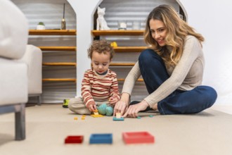 Young mother happily interacting with her toddler son, both sitting on a carpeted floor, engrossed