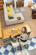 Happy mother and toddler boy sharing a morning meal at a kitchen island, creating a tender moment