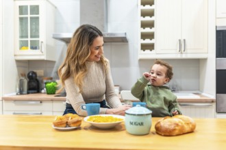 Mother smiles at her young child across the kitchen counter during a bright, cozy breakfast,