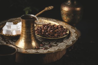 Turkish coffee next to sugar cubes and coffee beans, golden tableware, still life