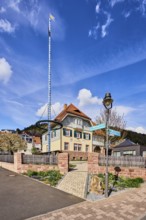 Town hall, maypole, lantern, sandstone wall, wooden fence, commercial building, hilly landscape,