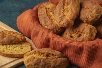 Fresh potato rolls in a basket with orange cloth, one cut open