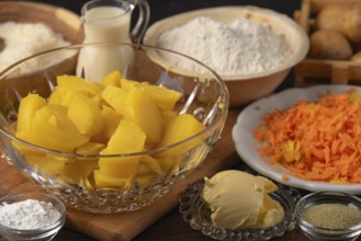 Sliced potatoes and grated carrots next to flour, milk and butter