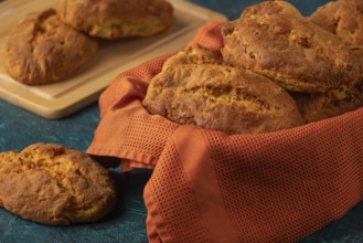 Fresh potato rolls in a basket with orange cloth, some presented on a wooden board