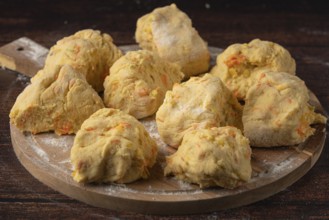 Several pieces of dough on a floured wooden board to prepare for baking