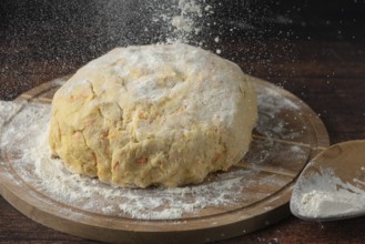 Dough is sprinkled with flour on a wooden board