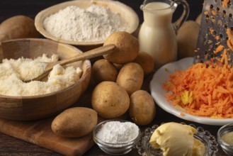 Grated cheese and carrots next to potatoes and flour