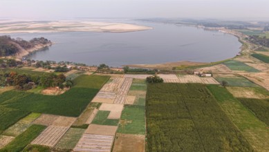Aerial view of cultivated farmland along the riverbank, with patchwork fields stretching toward a