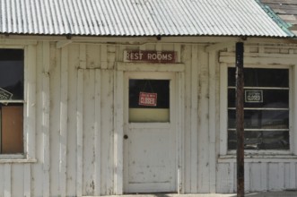 Old white door with 'Rest Rooms and Sorry We're Closed' signs on a wooden building, Stratton's