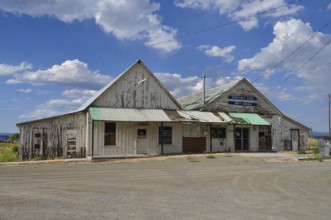 Two connected weathered buildings, Stratton's Store store, under blue sky with scattered clouds,