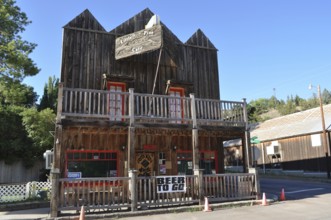 Two-story wooden building with porch and 'beer to go' sign under blue sky, Mitchell, Oregon, USA