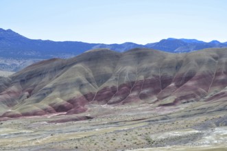 Colourful hills with red stripes under clear skies. Impression of an eroded geological formation,