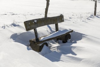 Wooden bench on the roadside with snowdrift, Altenberg, Eastern Ore Mountains, Saxony, Germany