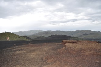 Red lava rock and hills under dramatic sky, Craters of the Moon National Monument, Idaho, USA