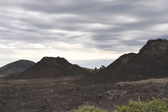 Volcanic landscape with gloomy clouds and several lava rock volcanic cones, Craters of the Moon