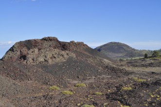 Landscape with volcanic hills, lava rock, sparse vegetation and clear sky, Craters of the Moon