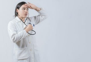 Young female doctor hearing Her Own Heartbeat with Stethoscope. Asian Female Doctor Listening to