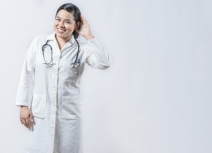 Asian doctor with hand on ear listening to a rumor isolated. Smiling female doctor hearing a rumor,