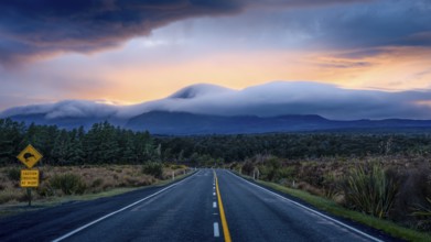Mount Ngauruhoe in the morning at sunrise with glowing clouds, road SH 47, road sign, warning sign