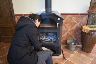Back view of an Asian woman is cleaning the wood burning stove ashes, preparing it for use, paying