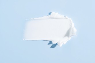 High-quality image showcasing a smooth, white cream smear isolated on a serene blue background,