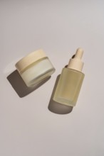Skincare jar and dropper bottle with minimalistic design on a neutral background The glass