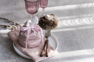 An artistic Easter table arrangement featuring a bunny-themed pink cloth wrap, elegantly tied,