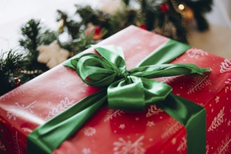 A beautifully wrapped Christmas gift in red paper with white snowflake designs, topped with a