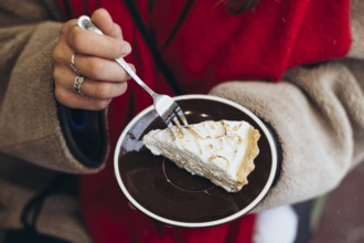 Cropped unrecognizable woman outside wearing winter garments, focusing on her hands as she uses a