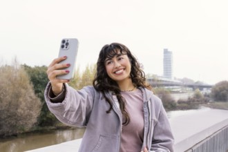A young Latin woman takes a selfie outdoors, capturing joyful moments The scene is set amidst a