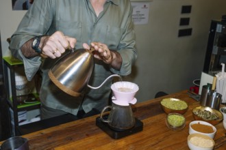A barista carefully pours hot water into a dripper, crafting specialty coffee with precision.