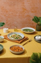 Lavish Italian dinner spread featuring bowls of basil pesto gnocchi, a fresh green salad, sweet