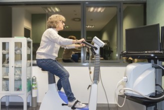A mature woman is actively participating in a cardiovascular stress test at a medical facility,
