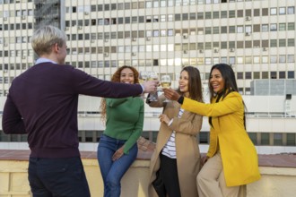 A joyful group of friends celebrating at a rooftop party, clinking glasses and smiling The festive
